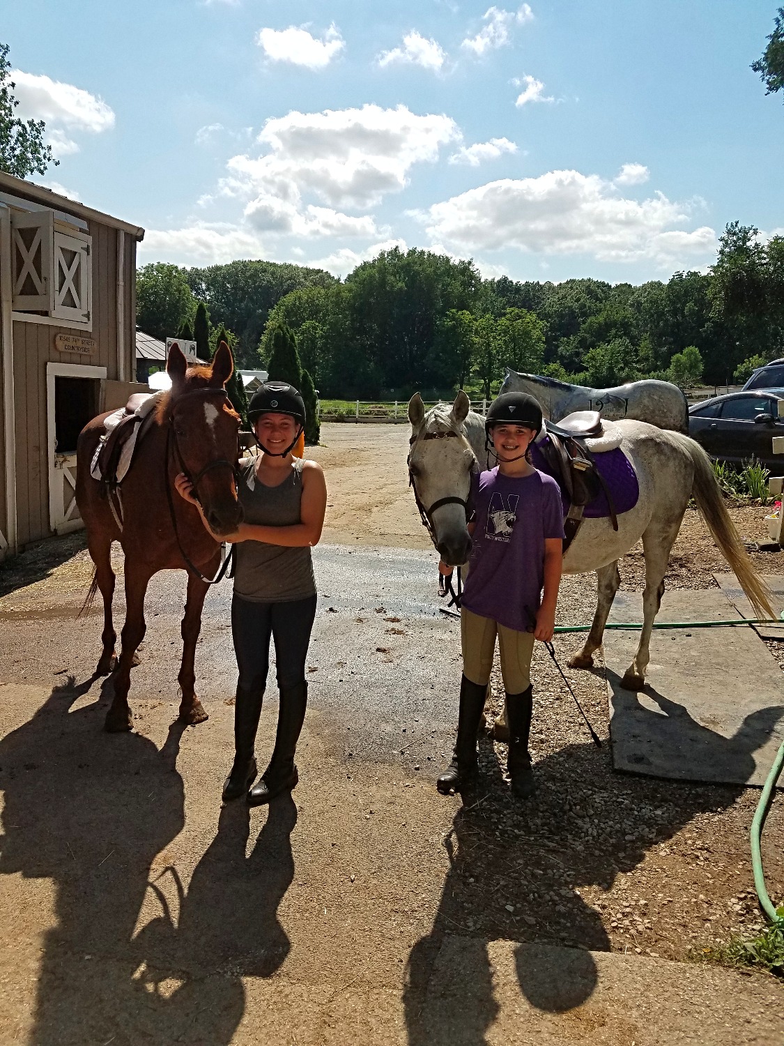 Two girls standing beside horses.