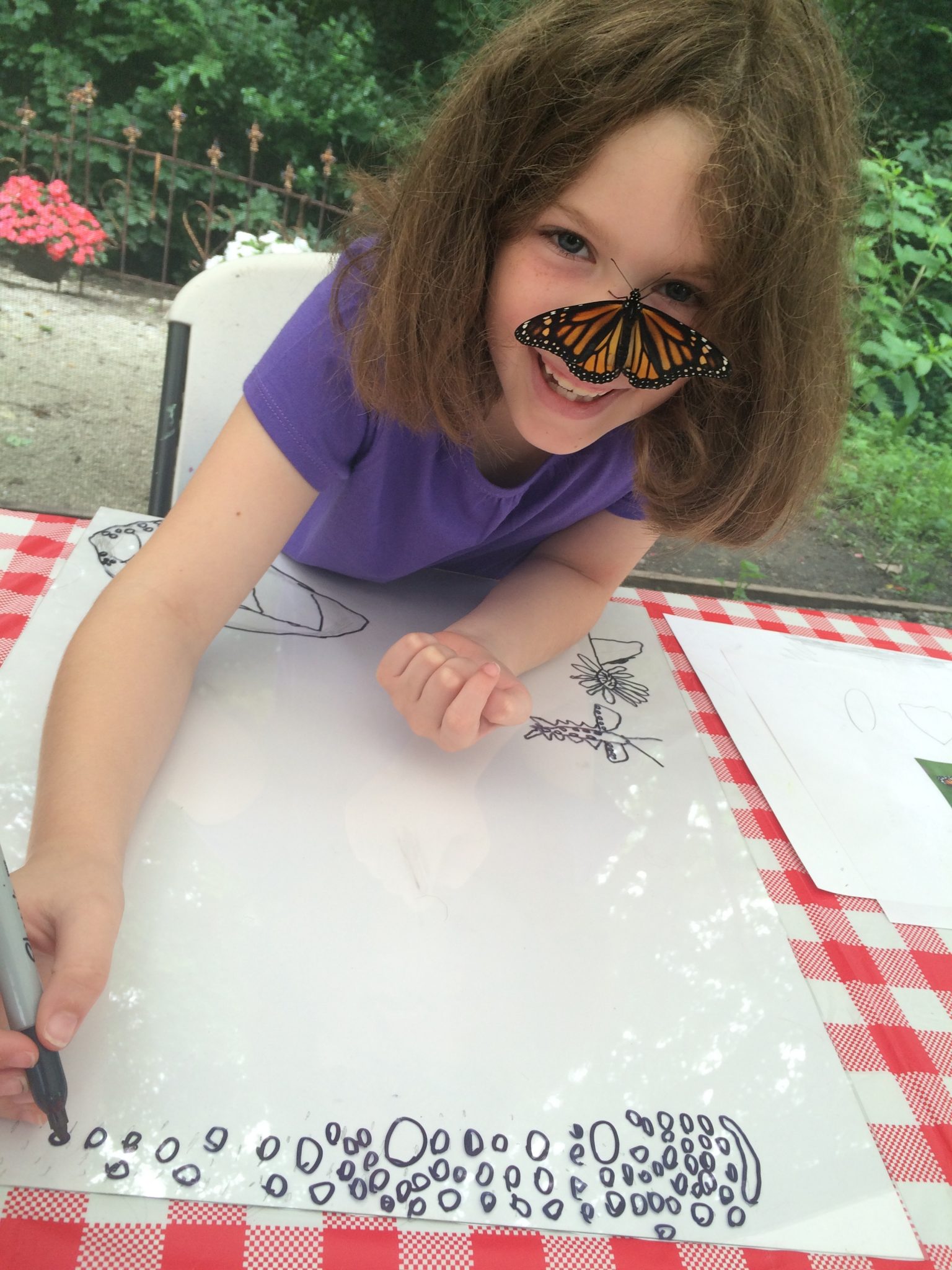 A young girl coloring with a butterfly on her face.