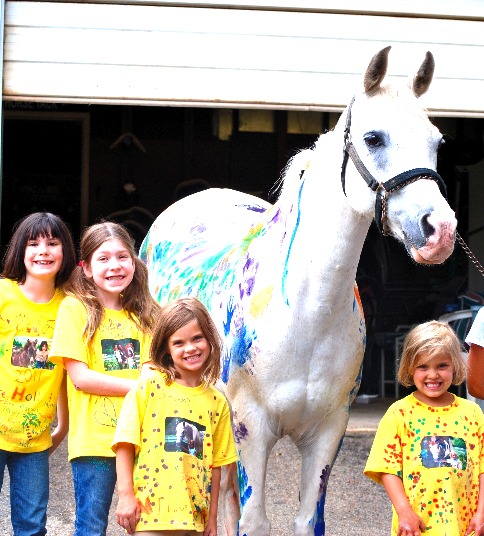 4 kids standing in front of a painted horse.