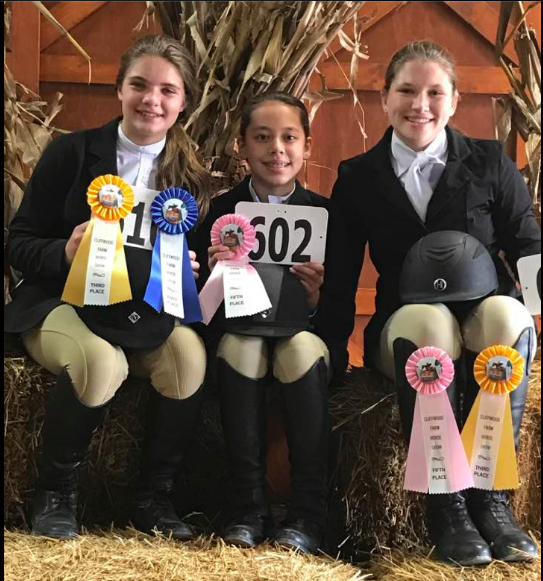 Three young girls presenting their won ribbons.