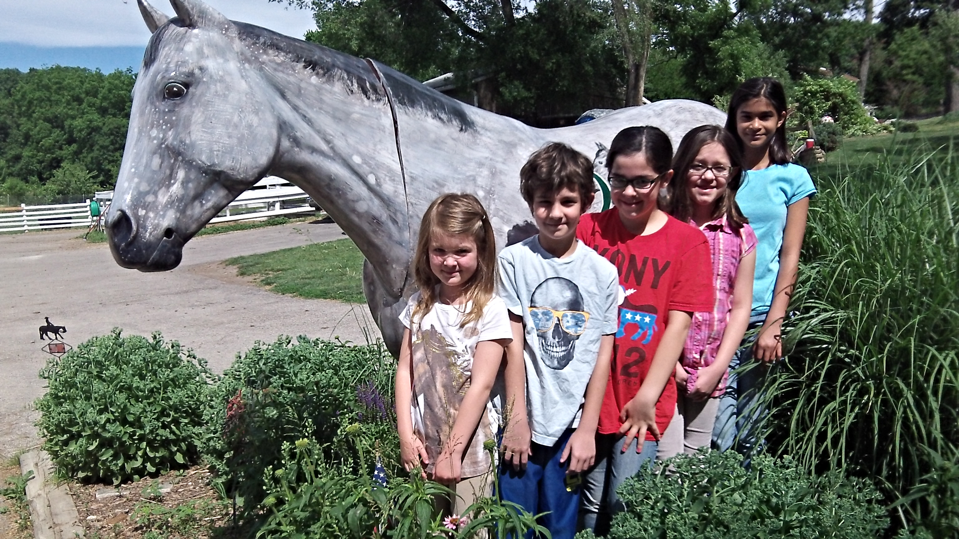 5 children standing in front of a horse statue.