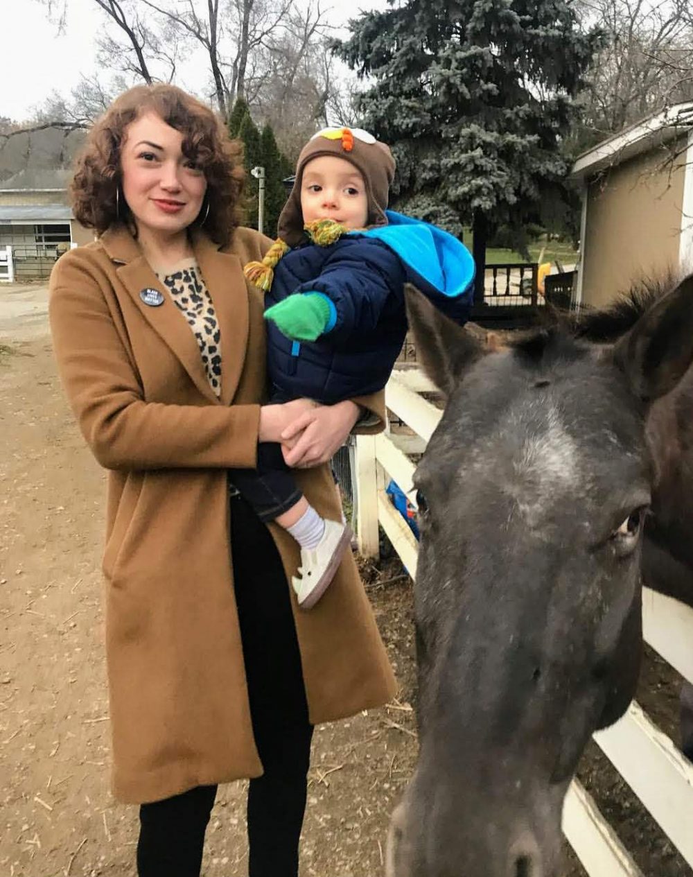 Mom holding child next to horse